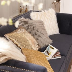 Neutral and metallic pillows layered on navy sofa